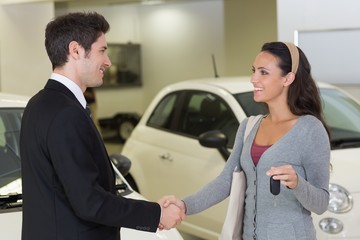 Businessman giving car key while shaking a customer hand