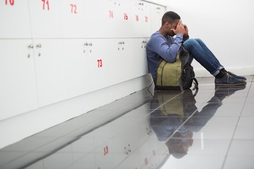 University student sitting alone with his hands on face