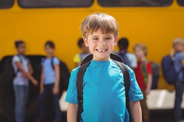 Cute pupils smiling at camera by the school bus