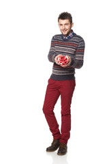 Naklejka premium Young man with a heart-shaped gift isolated on white background.