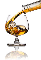 Pouring whiskey in glass with ice isolated on white