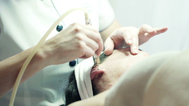 Woman getting microabrasion peeling on face at beauty salon