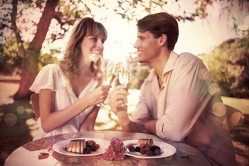 Cute happy couple sitting outside toasting with champagne