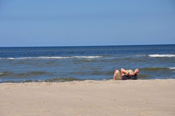 An der Nordsee. Der weiße Strand und das blaue Meer mit Tourist. Ein Mann entspannt liegend am...