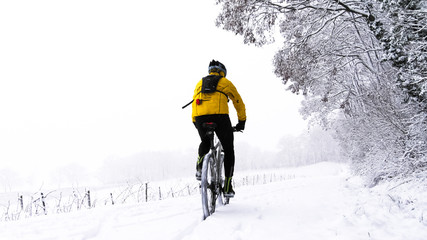 Winter-Training: mit dem Mountainbike durch eine verschneite Landschaft - obrazy, fototapety, plakaty