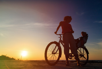 Obraz na płótnie Canvas mother and baby biking at sunset