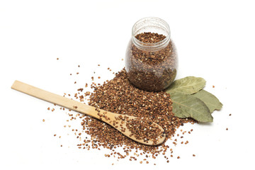 Buckwheat in the bank and a wooden spoon with bay leaf. Photo.