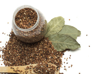 Buckwheat in the bank and a wooden spoon with bay leaf. Photo.