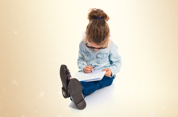 Naklejka premium Little girl with glasses writing