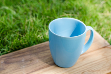 Obraz premium Blue mug on wooden board with green grass space.