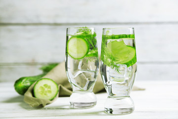 Glasses with fresh organic cucumber water on wooden table