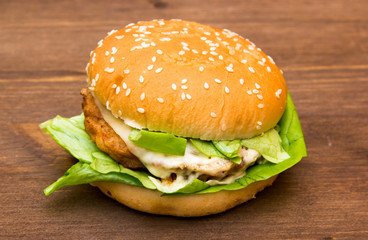 Hamburger with cheese and lettuce on wooden table