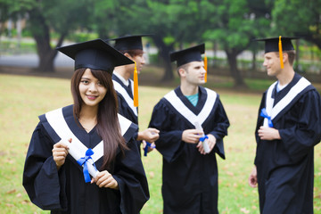 happy students in graduation gowns on university campus