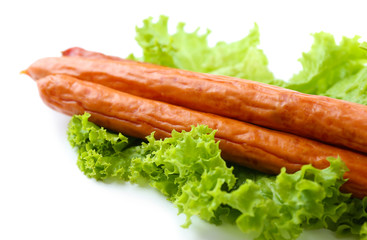 Smoked thin sausages  with lettuce salad leaves, isolated