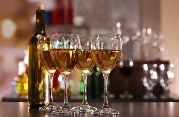 Glasses of wine on counter and bar on background