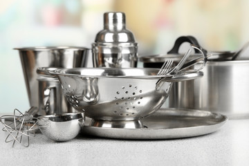 Stainless steel kitchenware on table, on light background