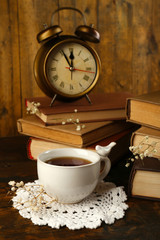 Obraz na płótnie Canvas Cup of tea with books and clock on wooden background