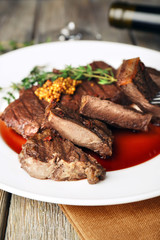 Steak with wine sauce on plate on wooden table