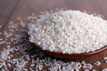 Grain of rice on plate on wooden background