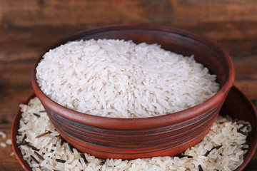 Grains of rice in bowls on wooden background