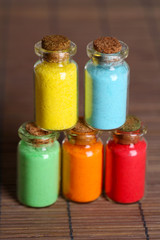 Bottles with colorful dry pigments on bamboo mat background