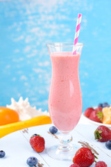 Delicious berry cocktail on table on water background