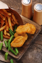 Breaded fried chicken nuggets and potatoes in paper bag with