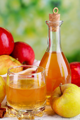 Apple cider in glass bottle with cinnamon sticks and fresh