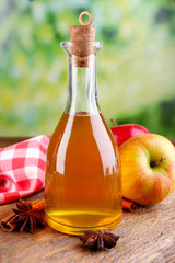 Apple cider in glass bottle with cinnamon sticks and fresh