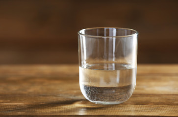 Glass of clean mineral water on rustic wooden background