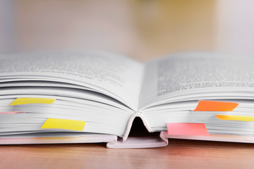 Book with bookmarks on table on bright background