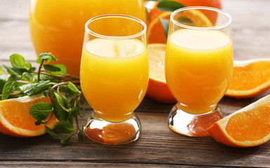 Glass of orange juice and slices on wooden table background