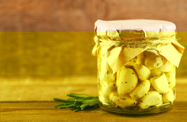 Canned garlic in glass jar on wooden background