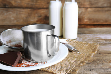 Metal mug and glass bottles of milk with chocolate chunks and