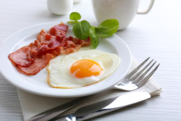 Bacon and eggs on color wooden table background