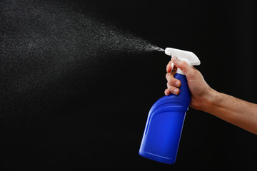 Male hand with sprayer on black background