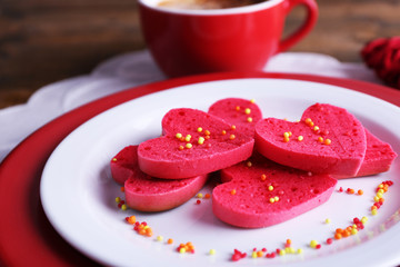 Cookies in form of heart in plate with cup of coffee