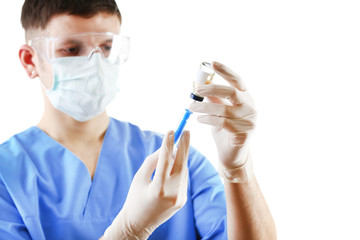 Doctor dialing medicine into syringe from glass bottle isolated