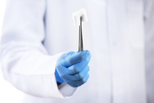 Doctor holding metal forceps with cheesecloth