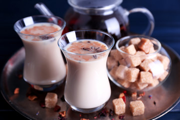 Black tea with milk in glasses and teapot with lump sugar