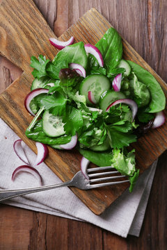 Mix salad leaves with sliced cucumber and onion