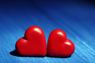 Two red hearts on color wooden table background