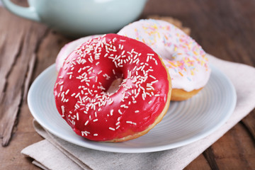 Delicious donuts with icing on plate on table close up