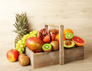 Assortment of exotic fruits in box on wooden background