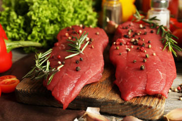Raw beef steak with spices and greens on table close up