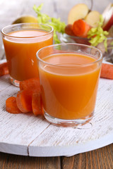 Glasses of juice with apple and carrot on wooden table close up