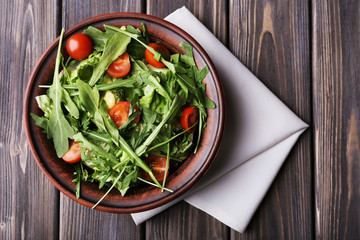 Salad with arugula and cherry tomatoes on wooden table