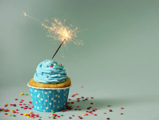 Cupcake with sparkler on grey background