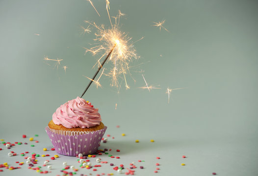 Cupcake with sparkler on grey background