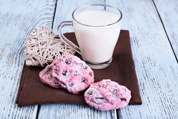 Pink cookies and cup with milk on table close-up
